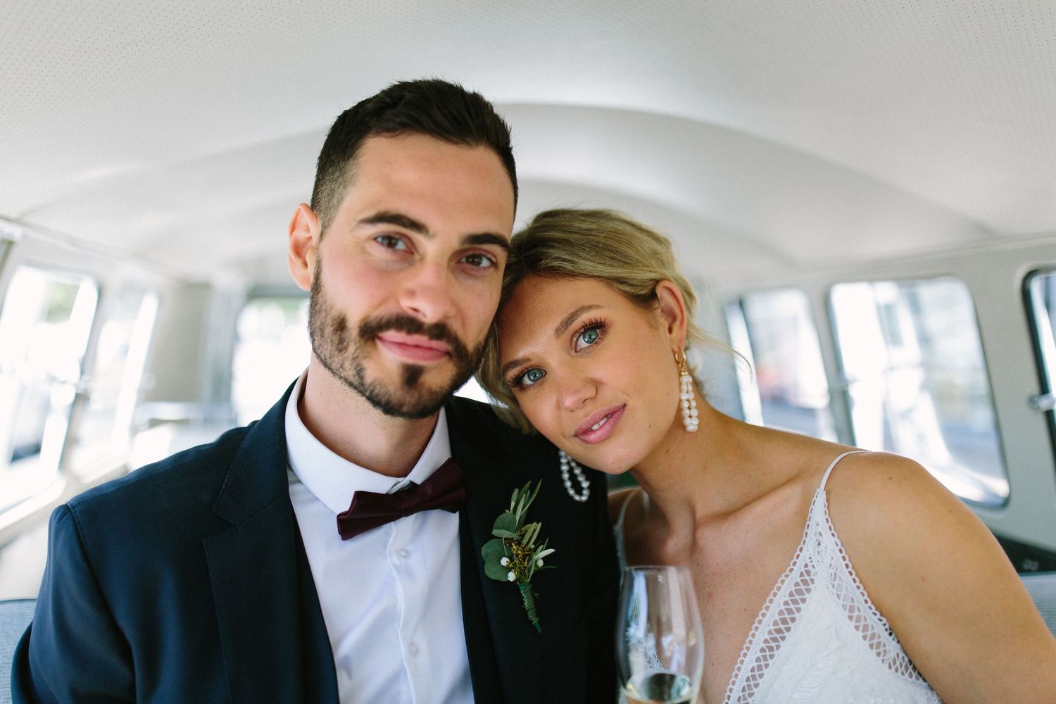 Couple taking selfies inside a classic car on their wedding day.