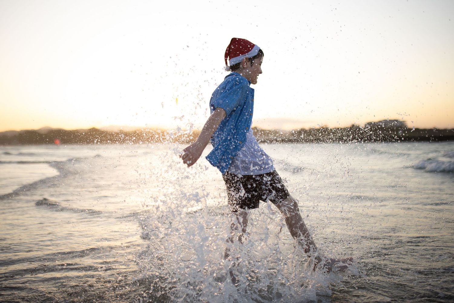 A person splashing and playing in the ocean water at sunset.
