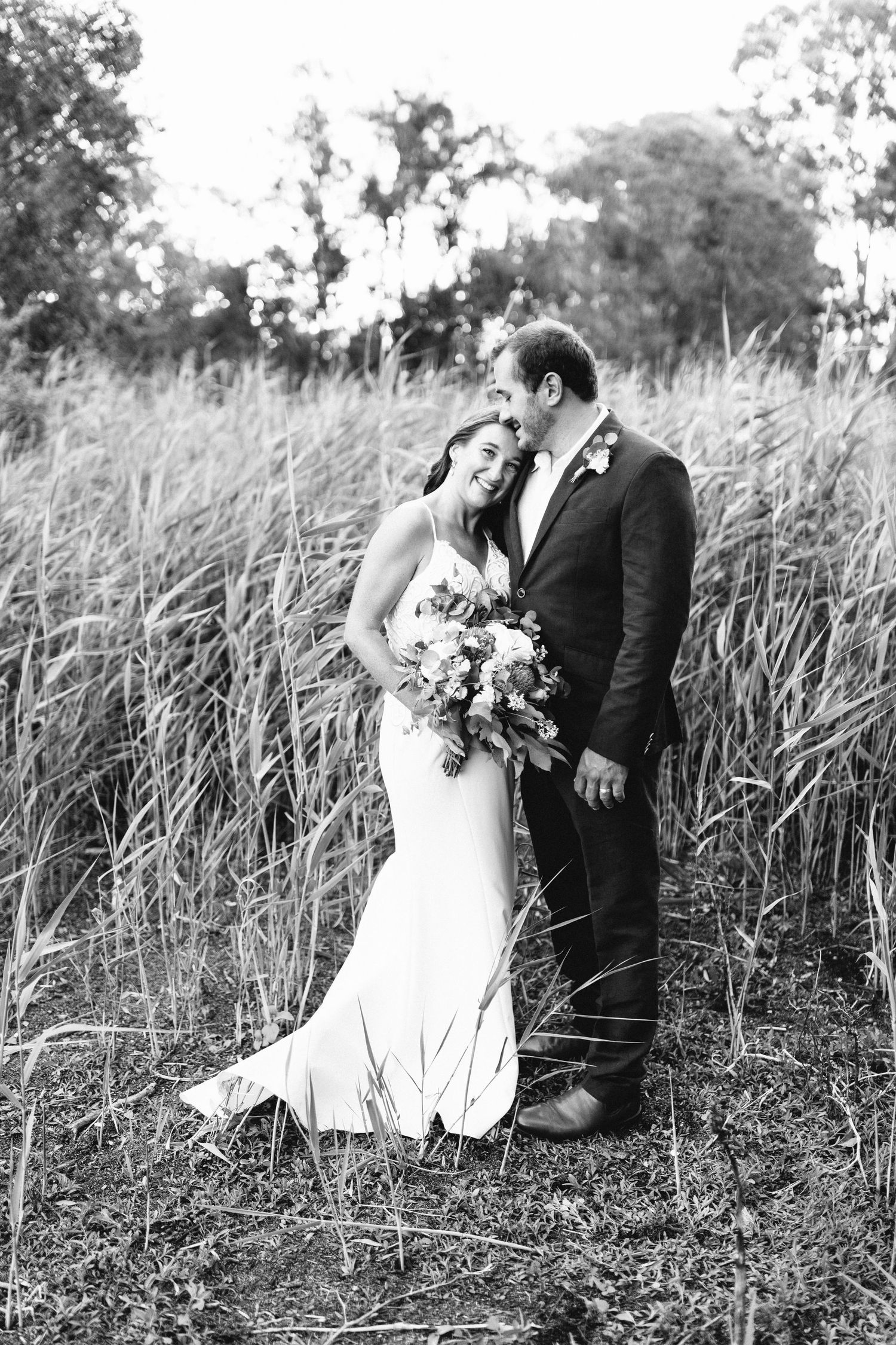 Black and white wedding photos of couple posing in tall grass field.