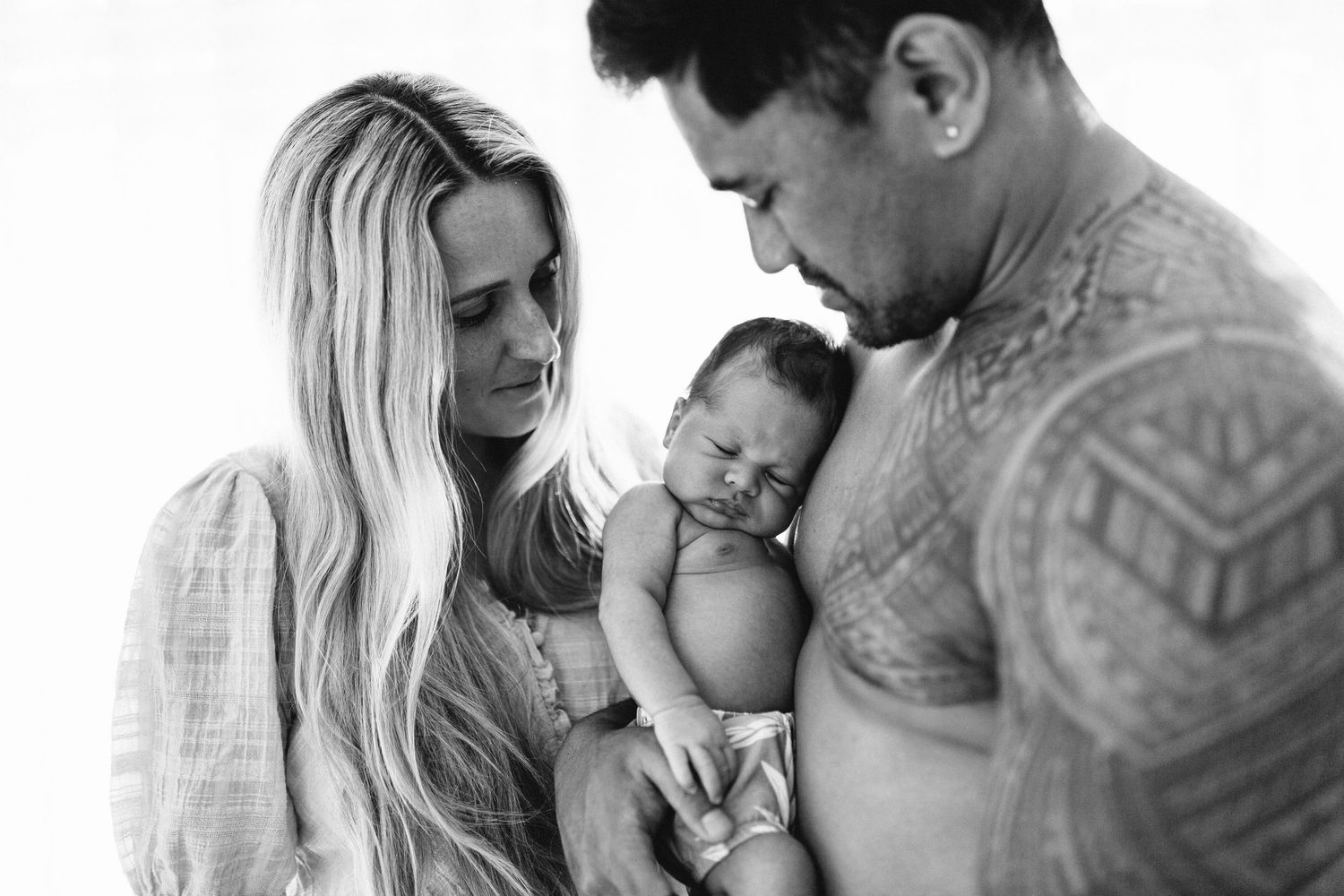 Intimate family moment with newborn baby in soft natural light.