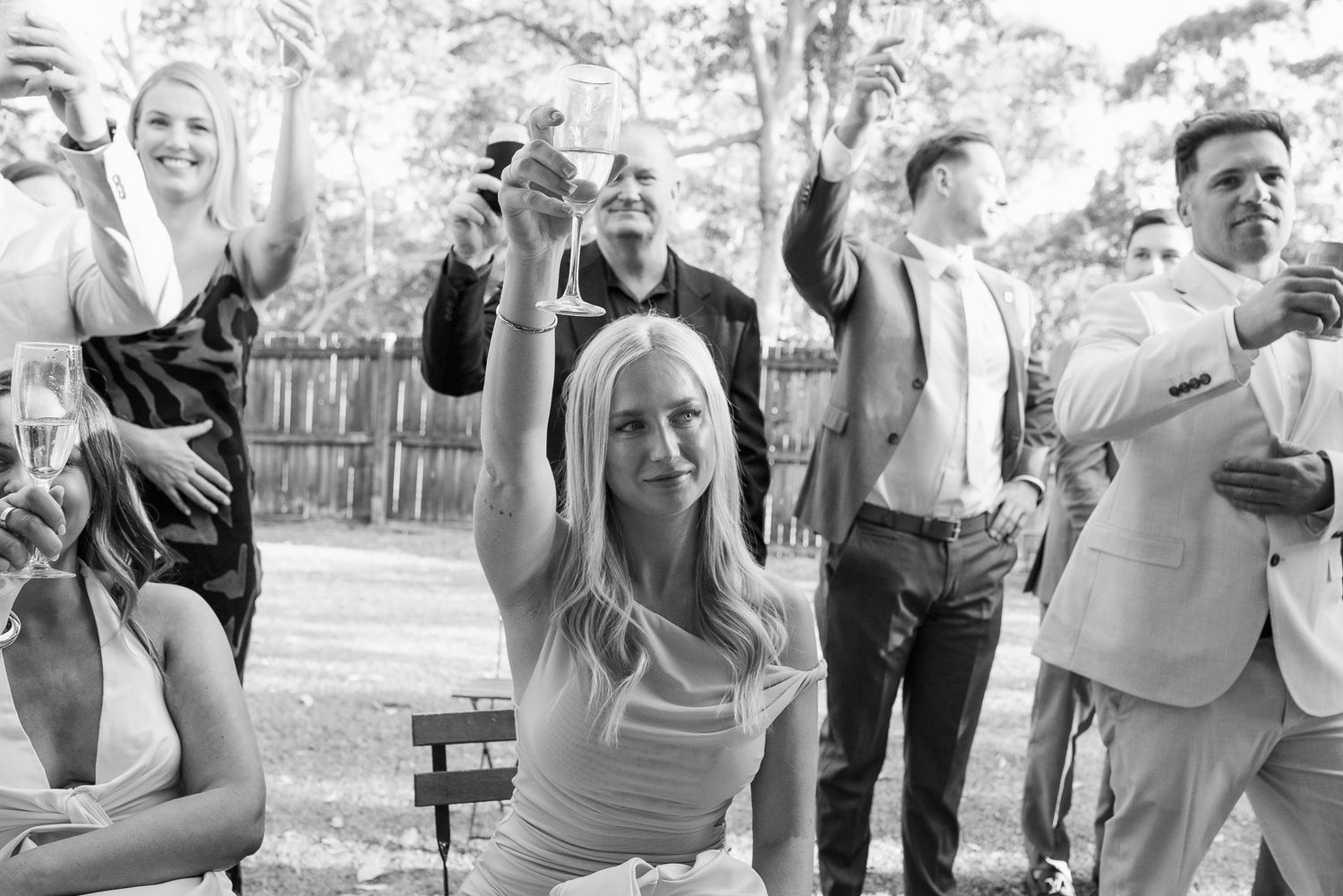 Wedding guests celebrating outdoors in black and white photography.