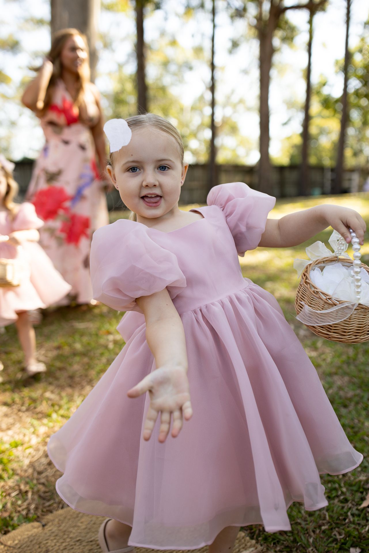 Children in pink dresses playing and twirling outdoors.