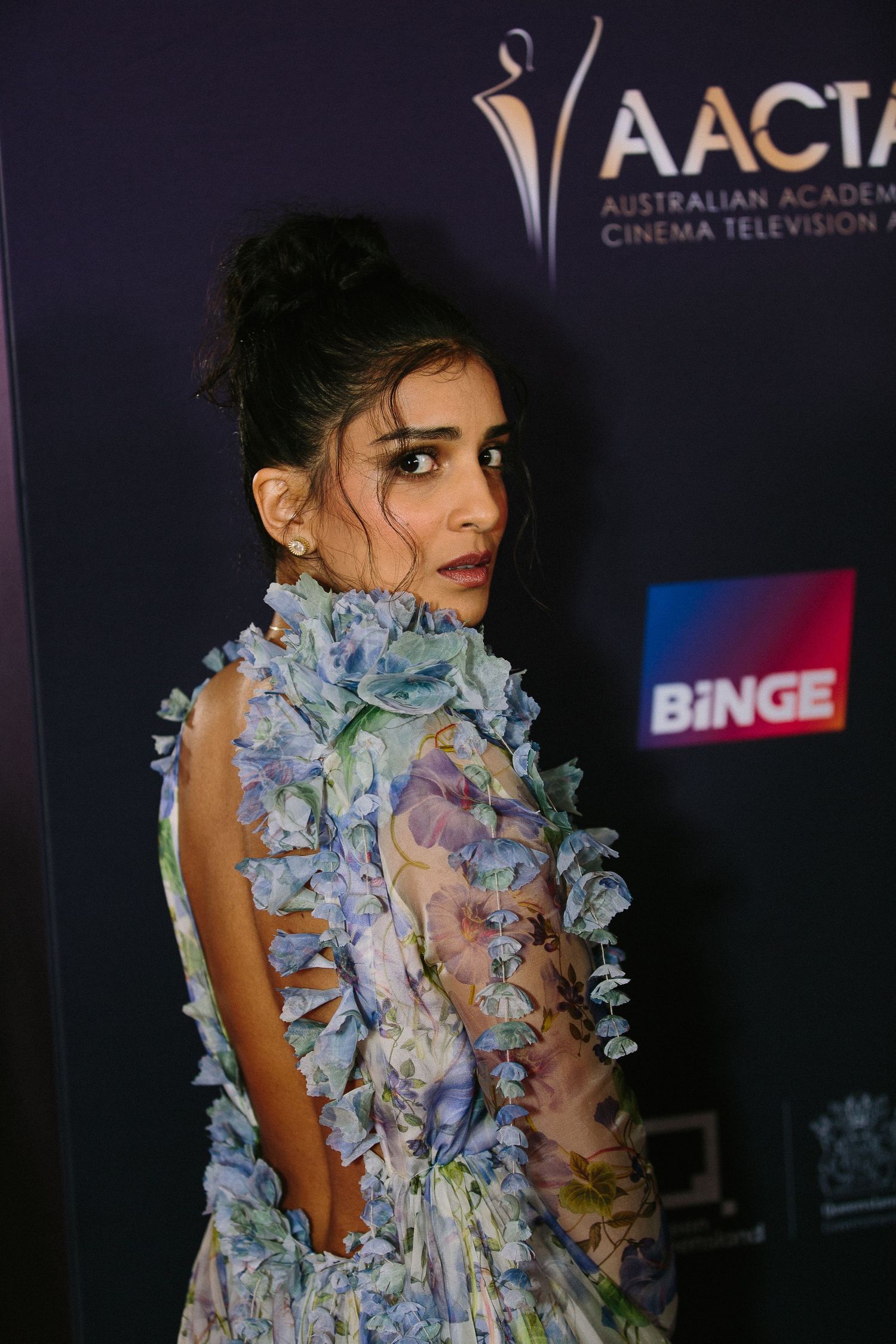 Elegant gown featuring delicate blue and white ruffled floral details against a dark backdrop at an awards ceremony.