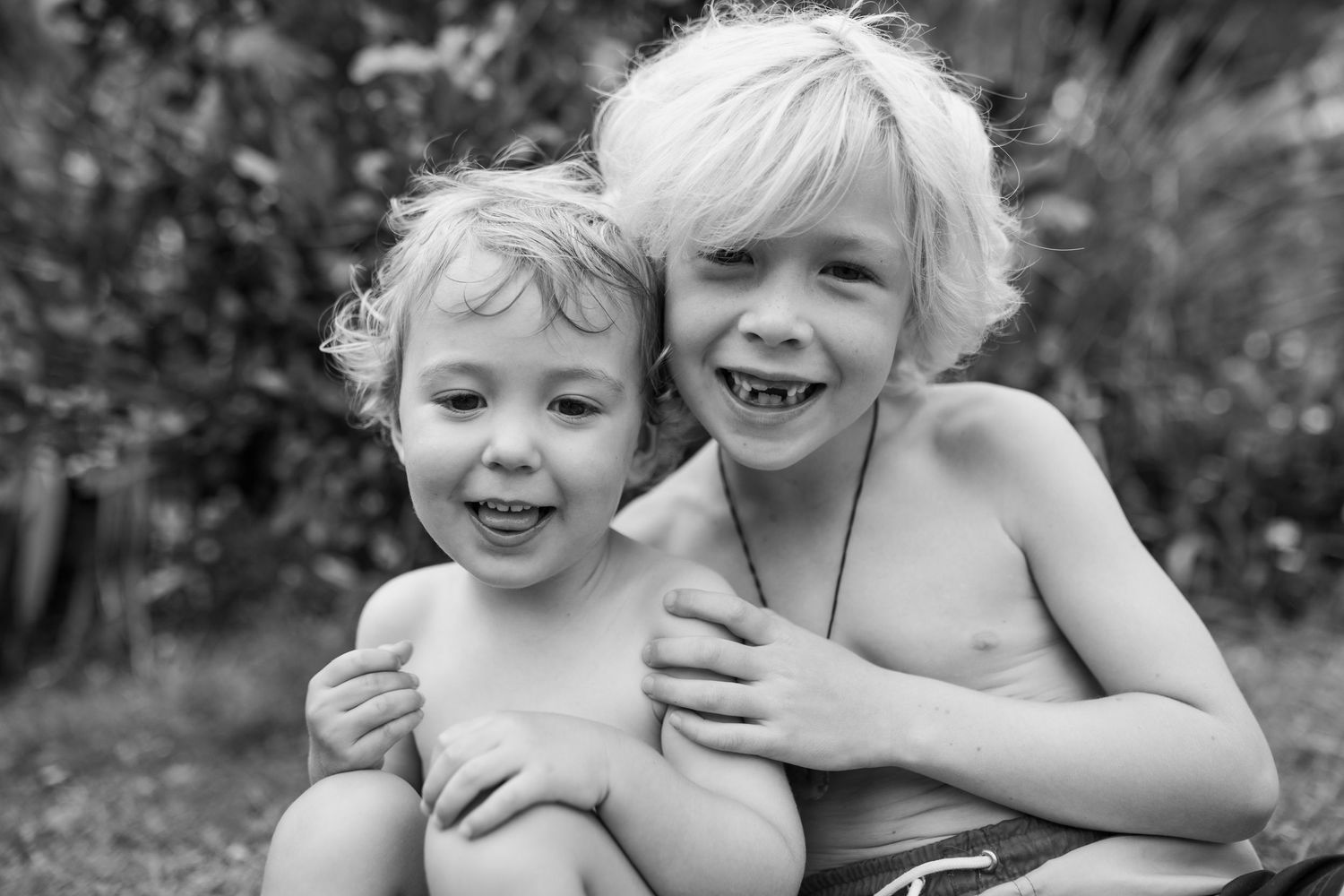 Two children hugging and laughing together outdoors.