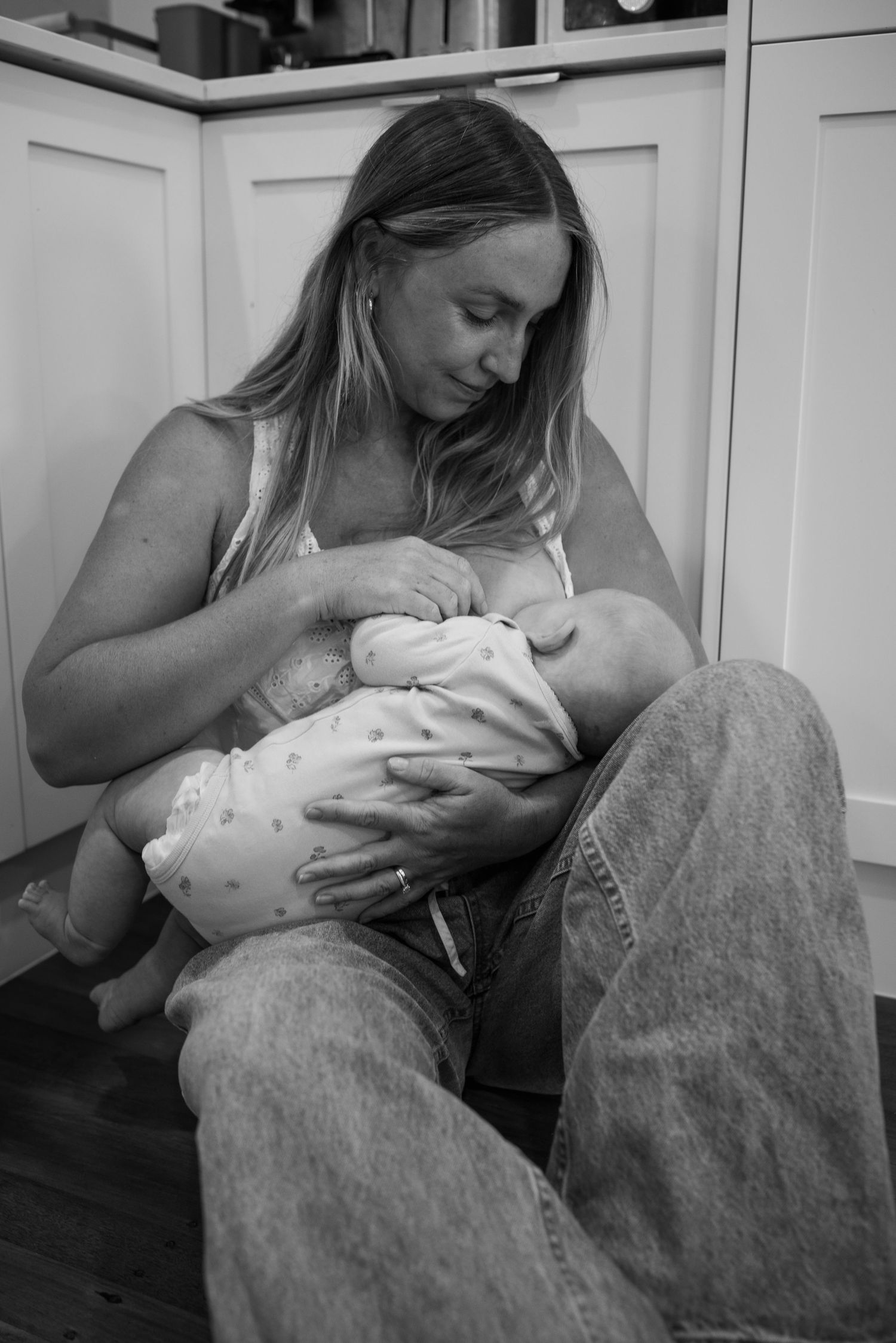 Intimate black and white photo of a nursing moment in a home setting.
