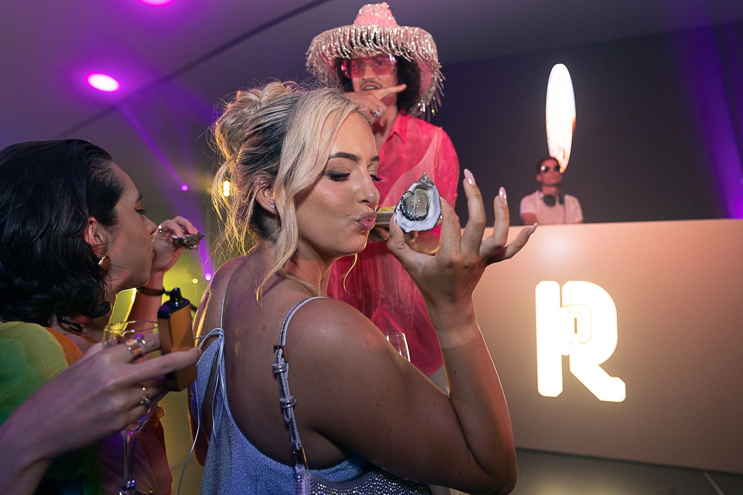 Nightclub scene with people dancing under purple lighting at an energetic party.