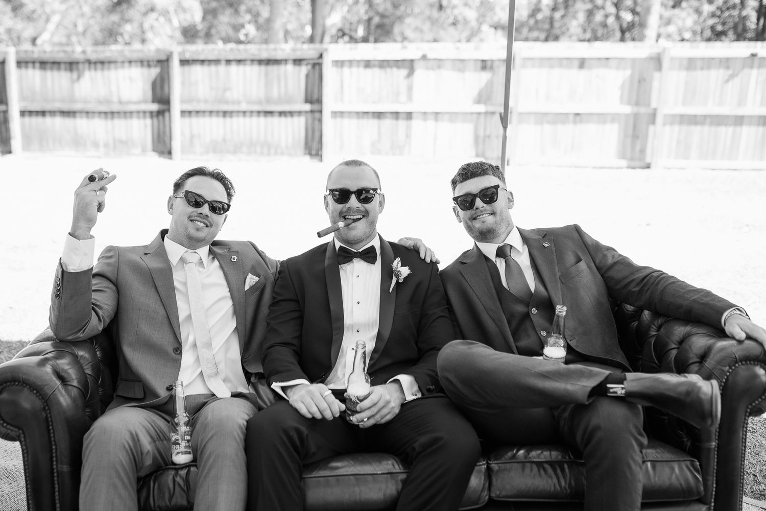 Black and white photos of groomsmen relaxing on outdoor furniture.