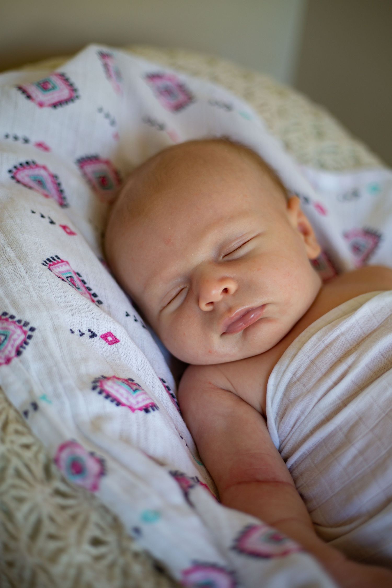 Peaceful sleeping newborn baby wrapped in floral patterned blanket.