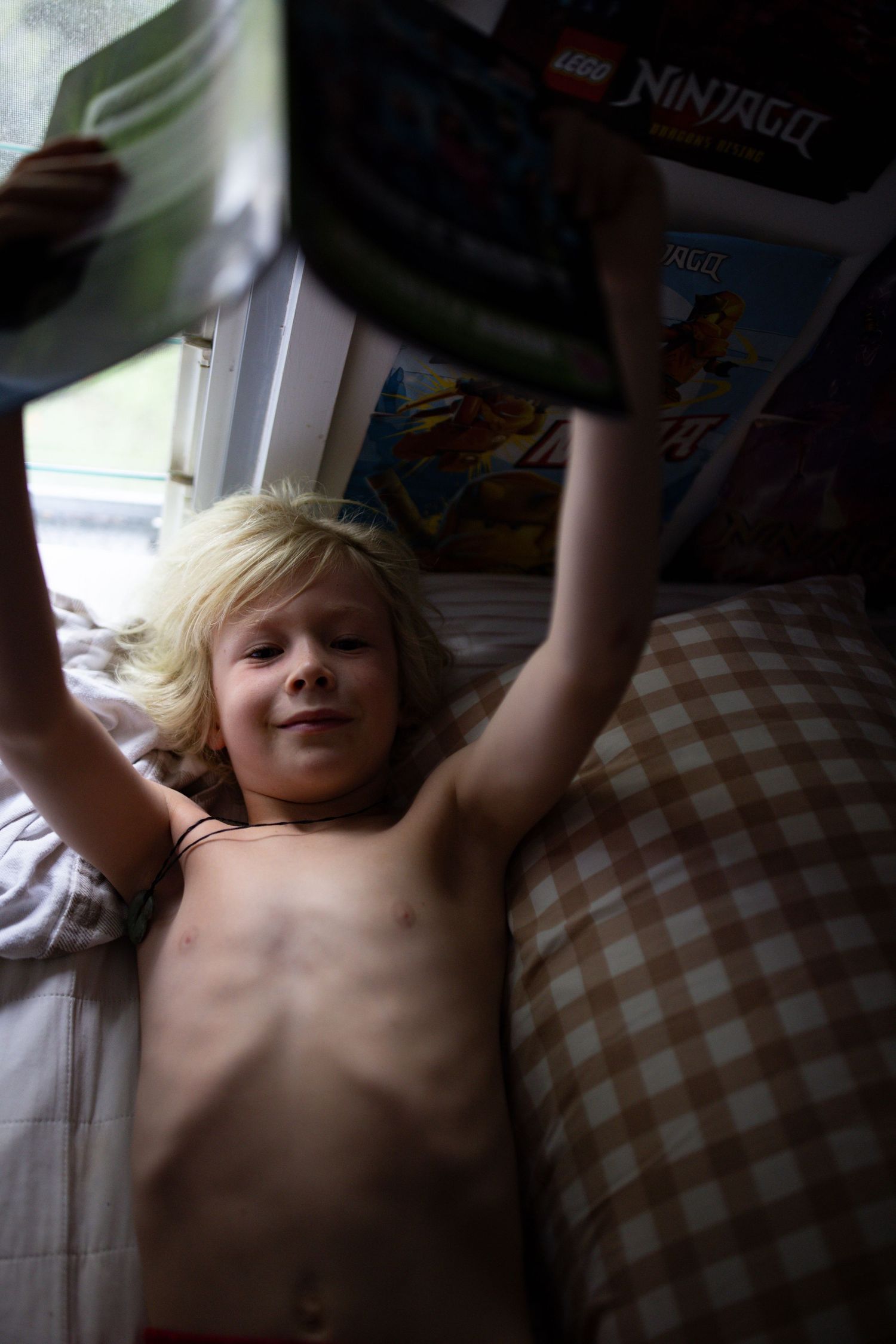 Child relaxing on plaid pillows in natural window light.
