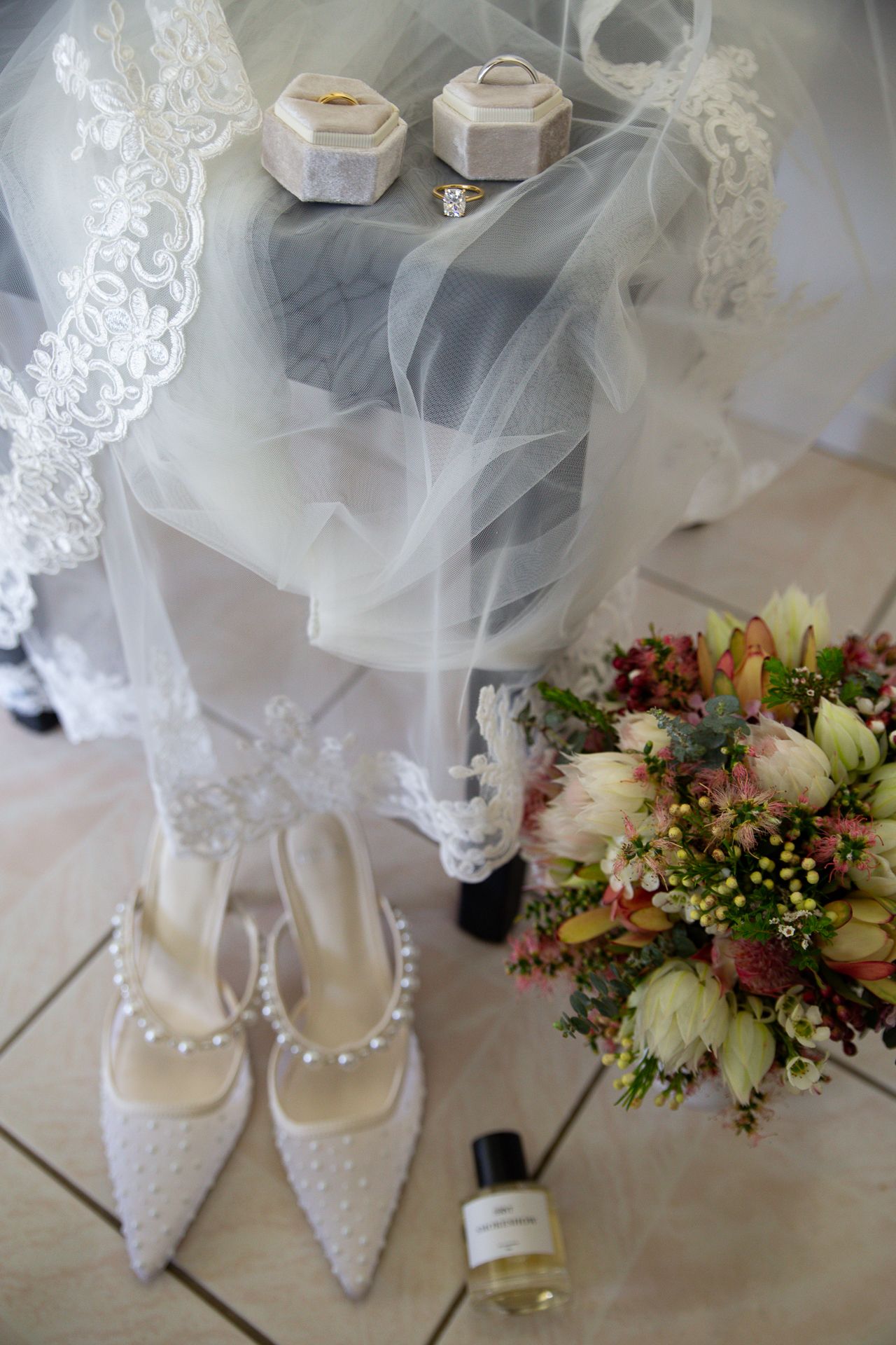 Wedding accessories including lace veil, pearl-adorned shoes and delicate floral bouquet.