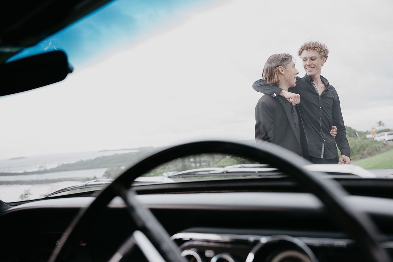 Romantic couple photos captured through a car windshield with coastal scenery.
