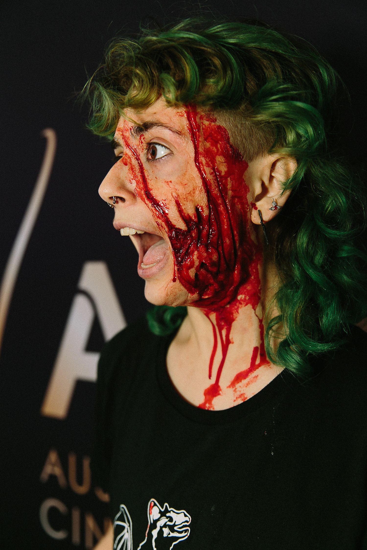 Dramatic close-up profile shots showing green hair and theatrical blood makeup effects against dark background.