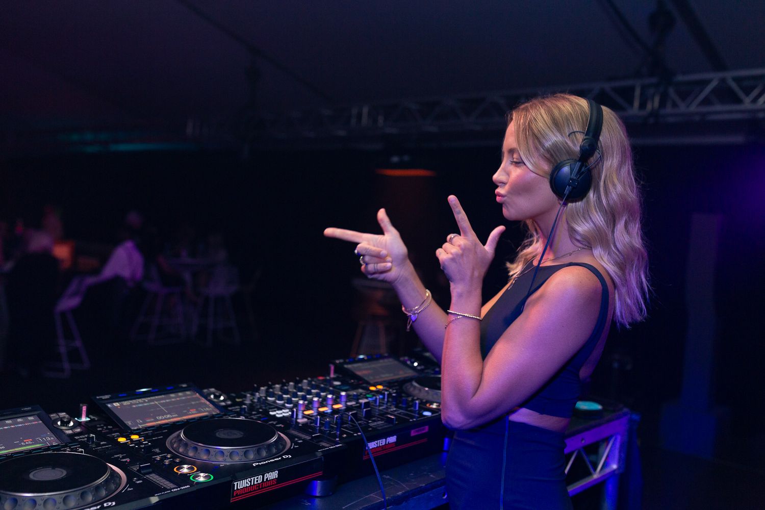 DJ performing at a nightclub with blue lighting and electronic equipment.