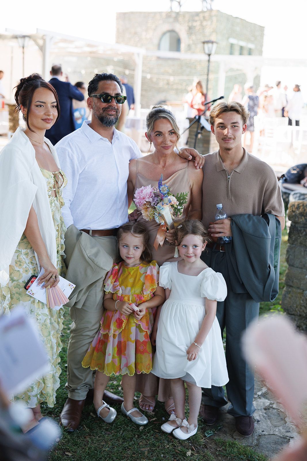 Group photo of wedding guests and children gathered outdoors at a celebration.