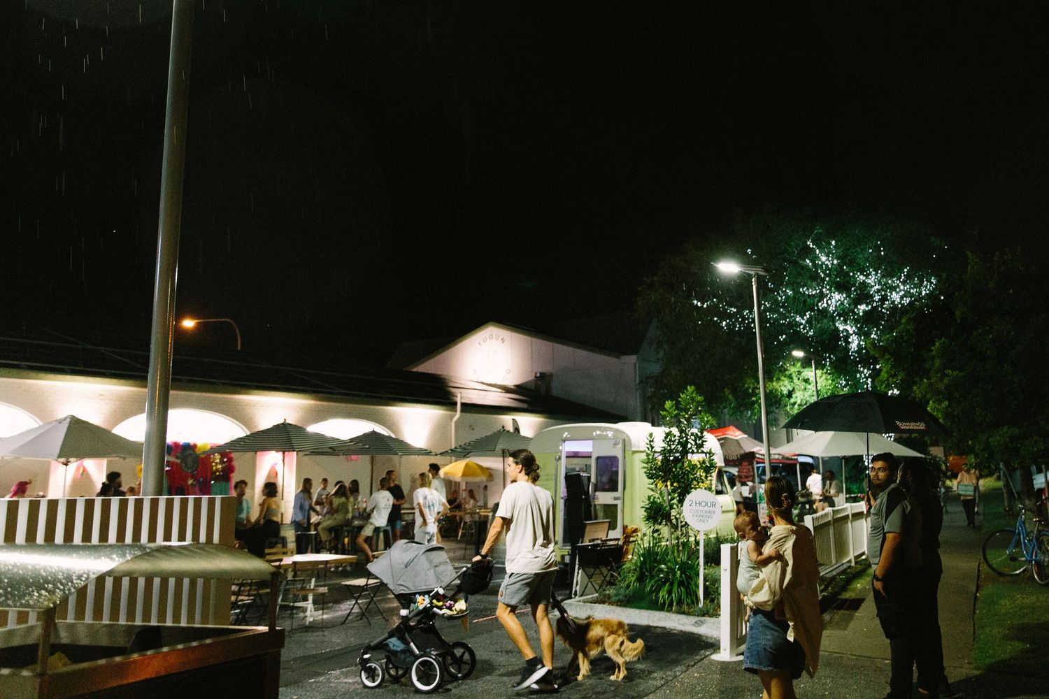 Outdoor evening event setup with white tents and lighting illuminating the nighttime venue.