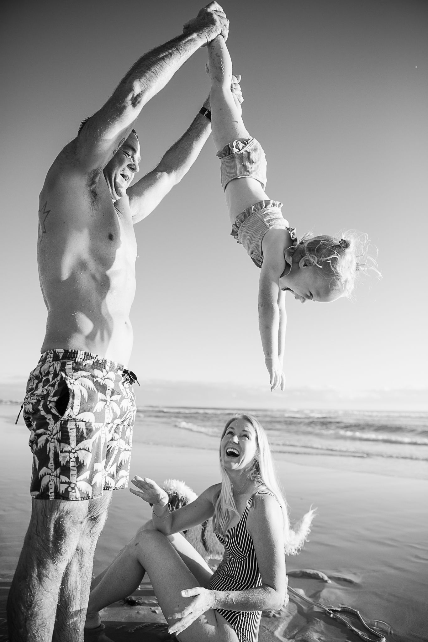 People enjoying playful moments at the beach in black and white photography.