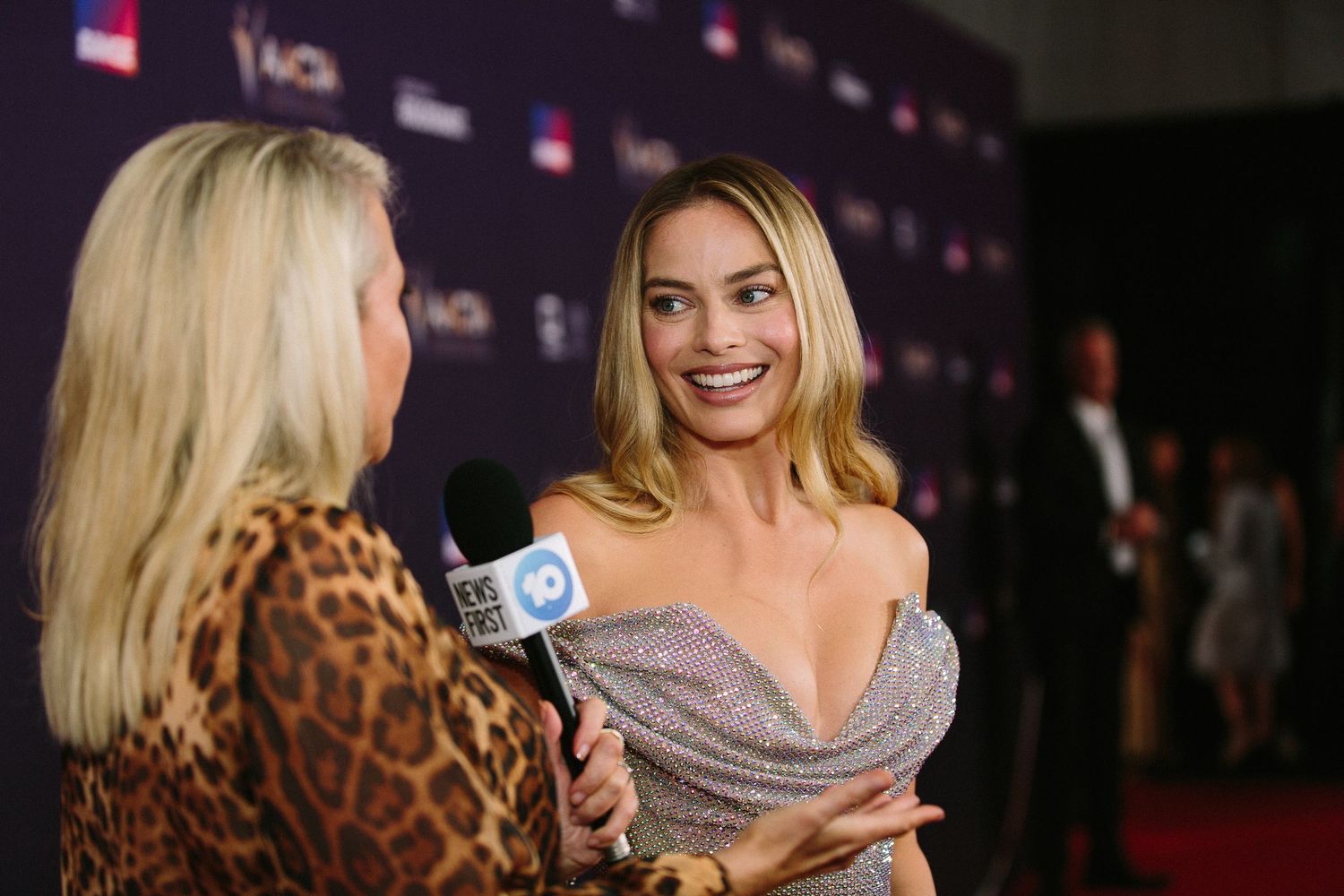 Glamorous red carpet event with attendees in formal attire under dramatic lighting.