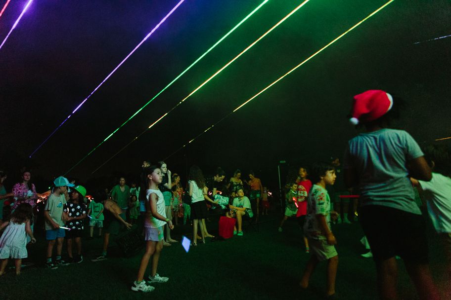 Concert venue with purple and green laser lights creating dramatic lighting effects.