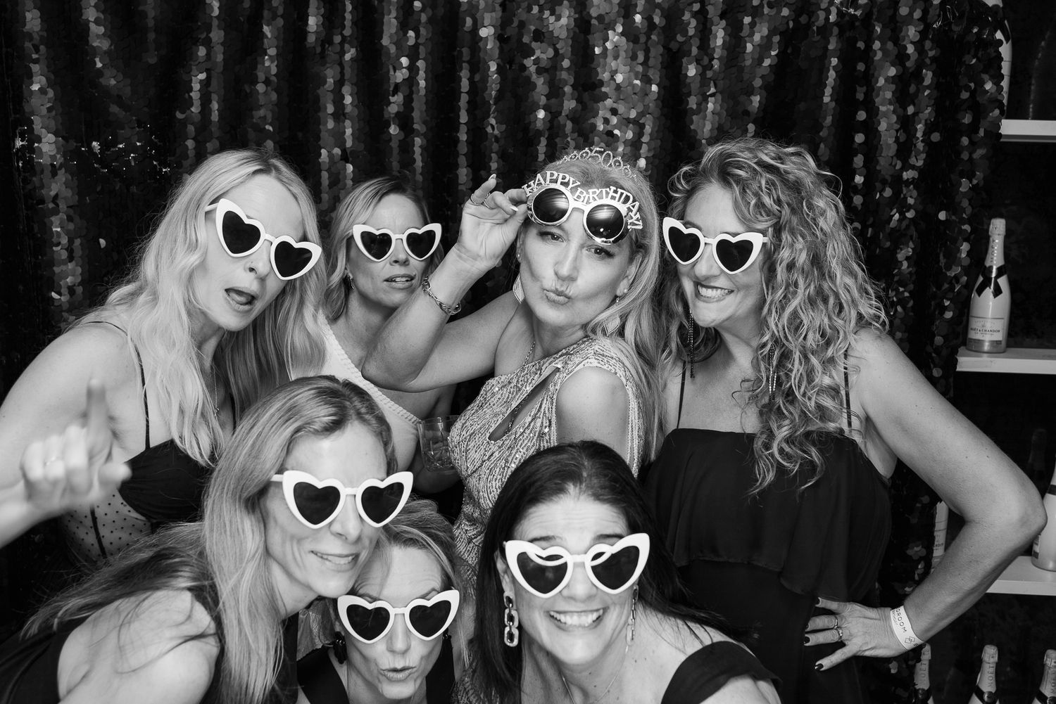 Group wearing white heart-shaped sunglasses posing together in black and white photo series.