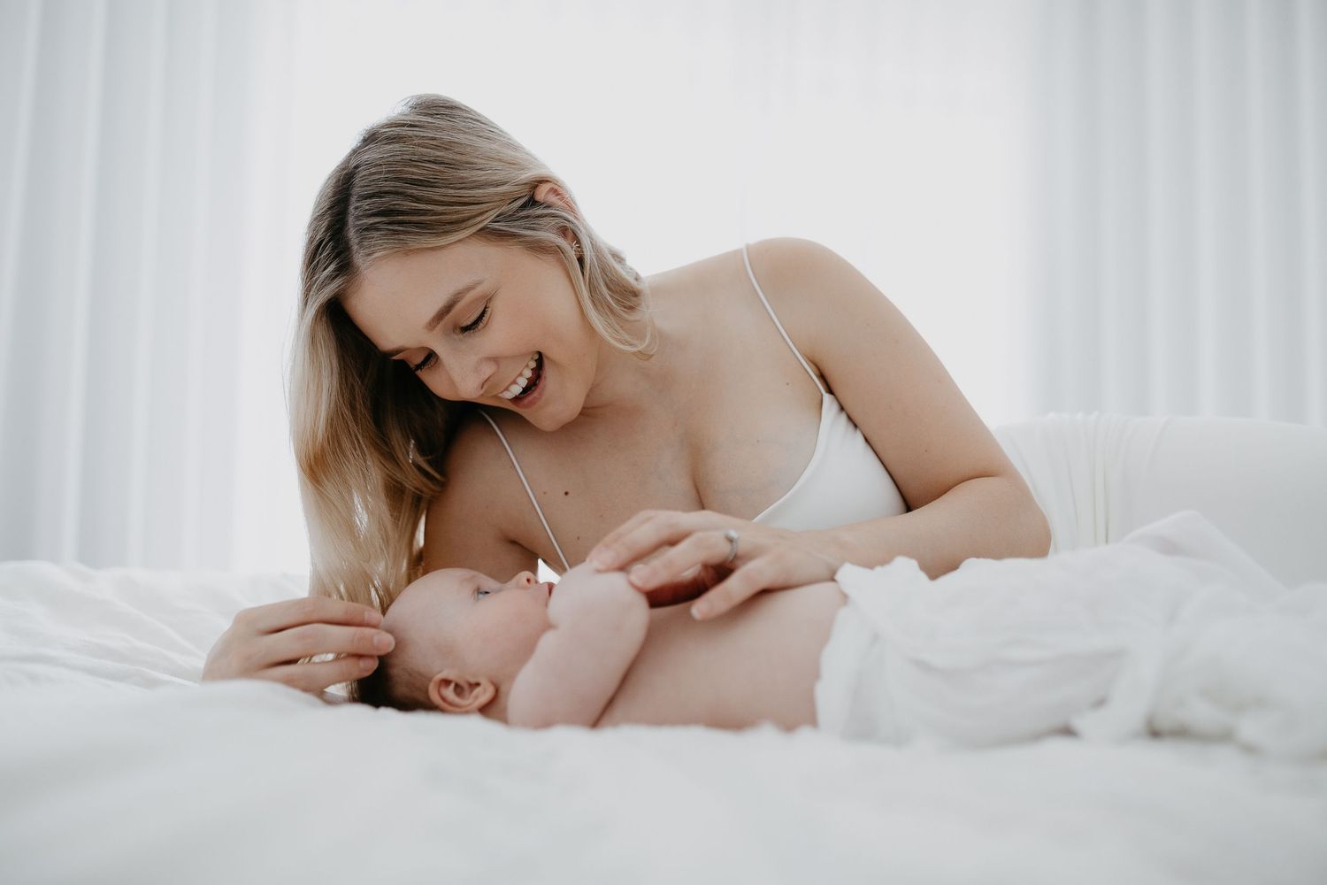 Tender moment captured between parent and baby in bright white setting.