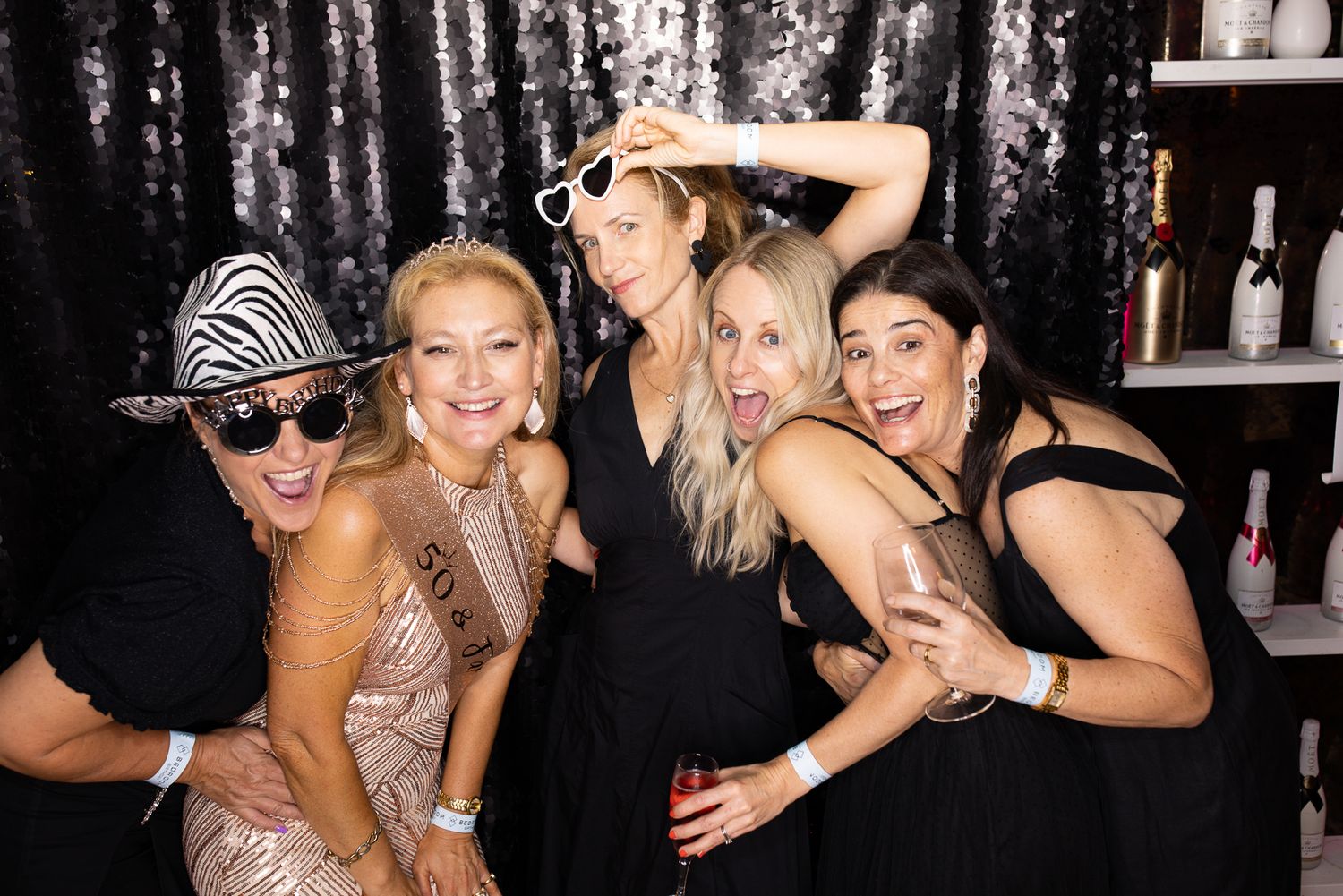 Party guests posing together for photos at a social gathering.