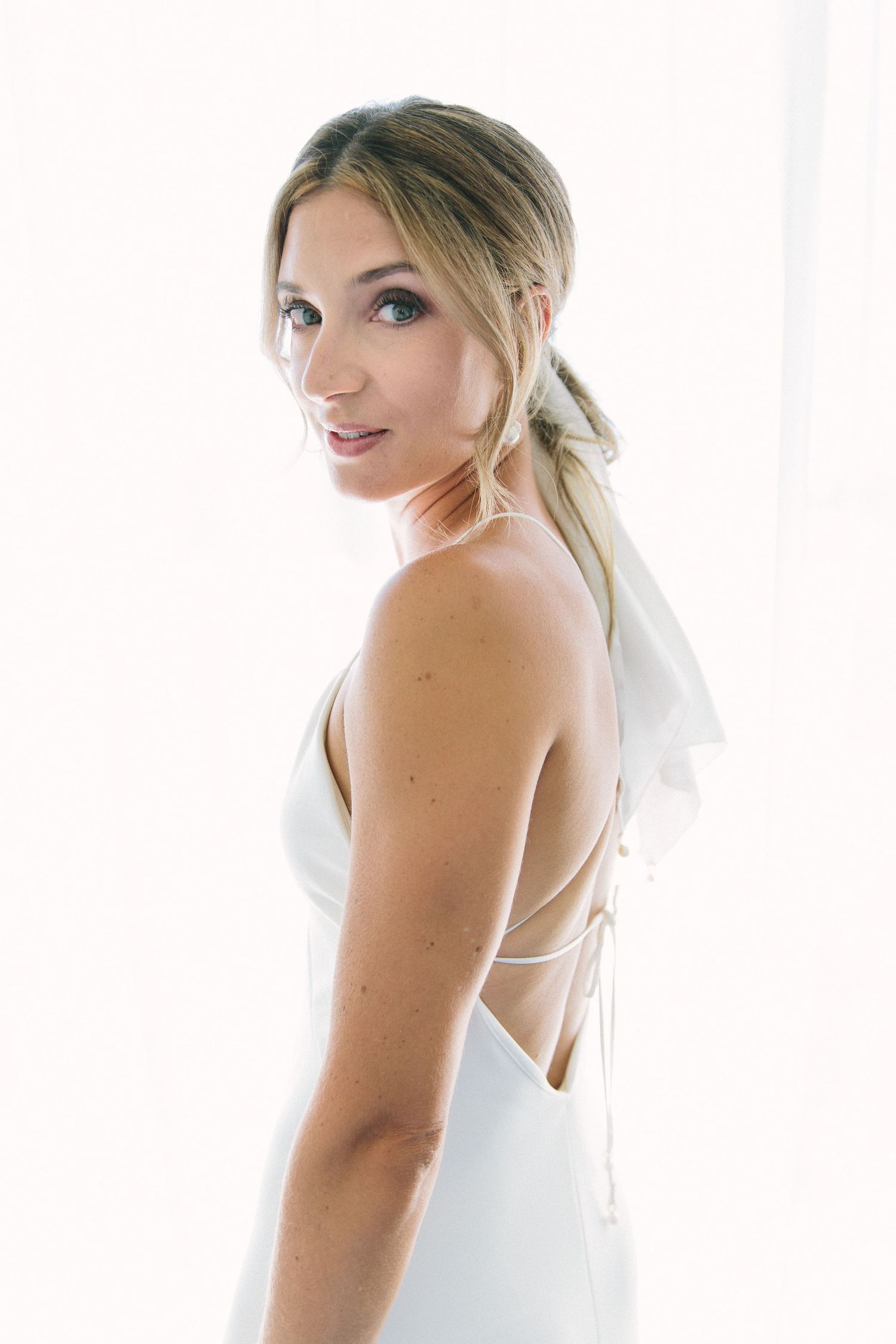 Bridal portraits against a bright white background showing elegant wedding dress details.