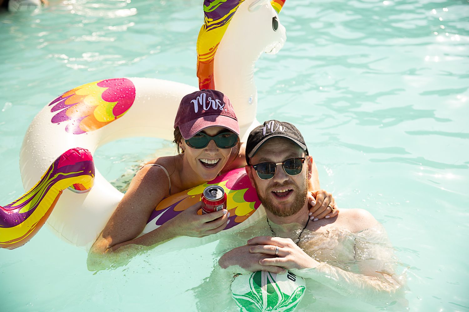 People enjoying a pool party with colorful pool floats in turquoise water.