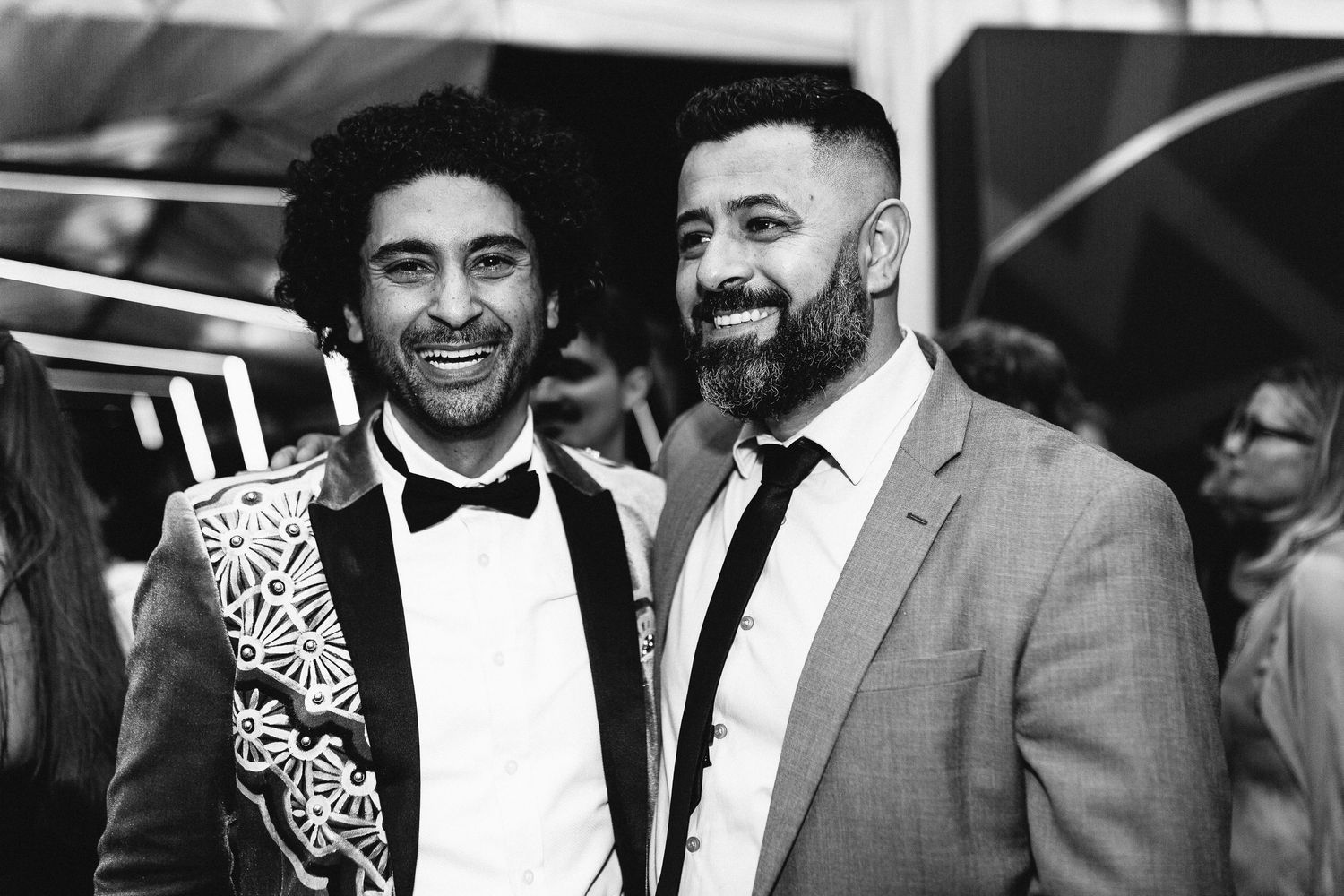 Formal event attendees in black tie attire sharing laughs at an awards show.