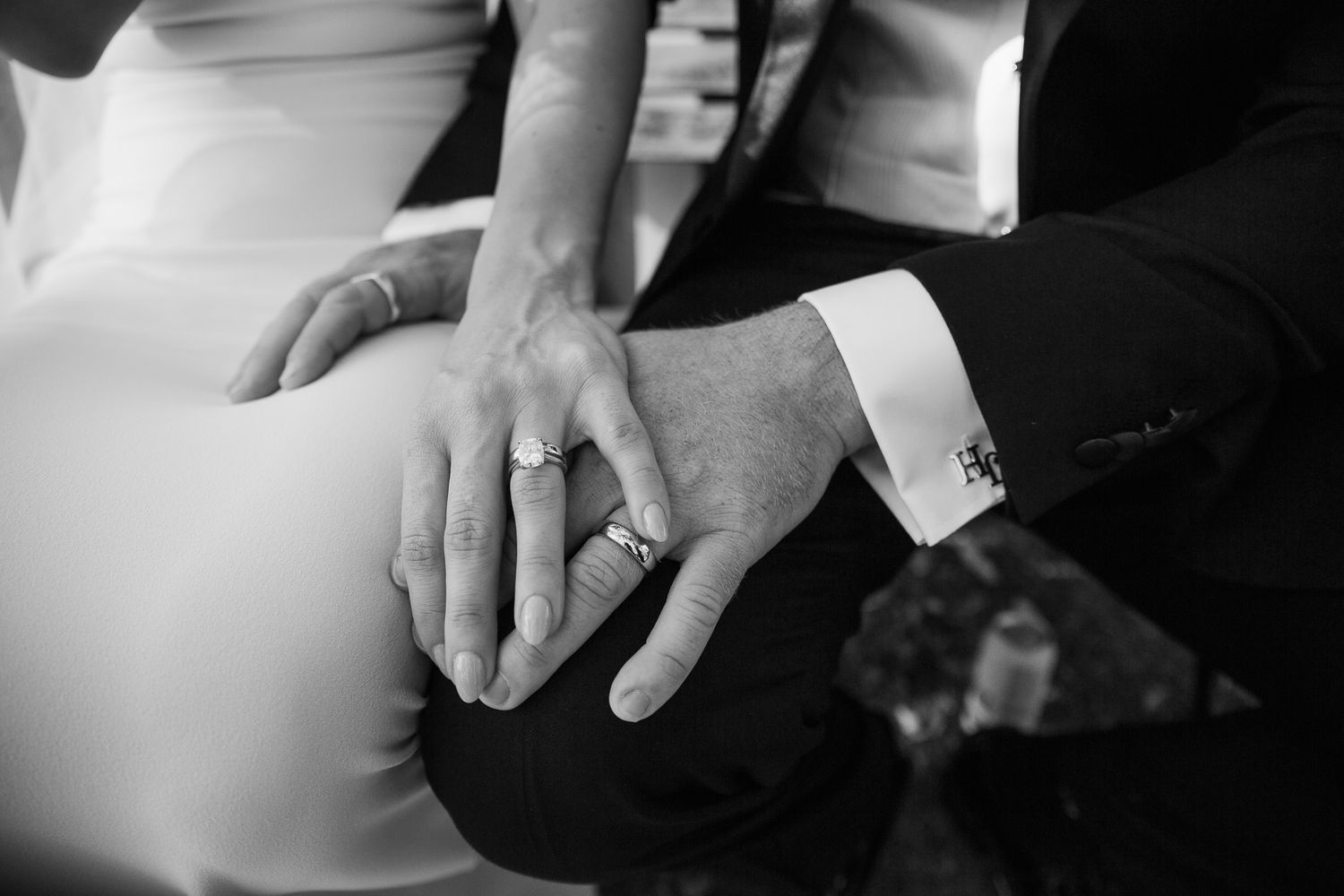 Close-up black and white detail of hands with wedding rings.