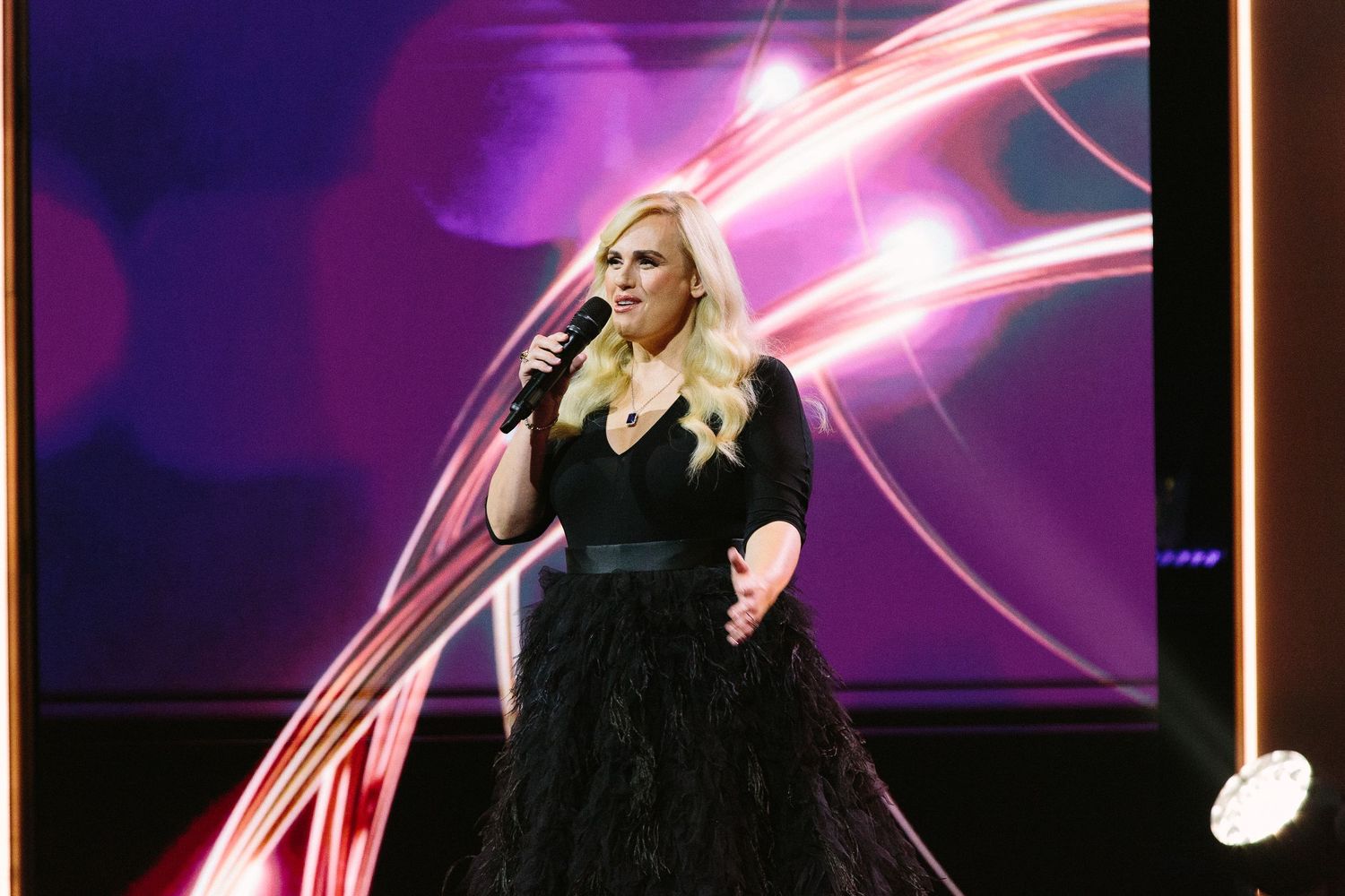 Pink neon lights illuminate a dark stage at an entertainment awards show.