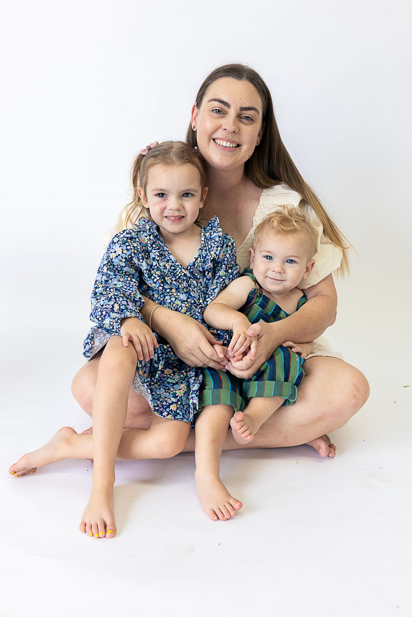 Family sitting together on white background wearing coordinated blue and green outfits.
