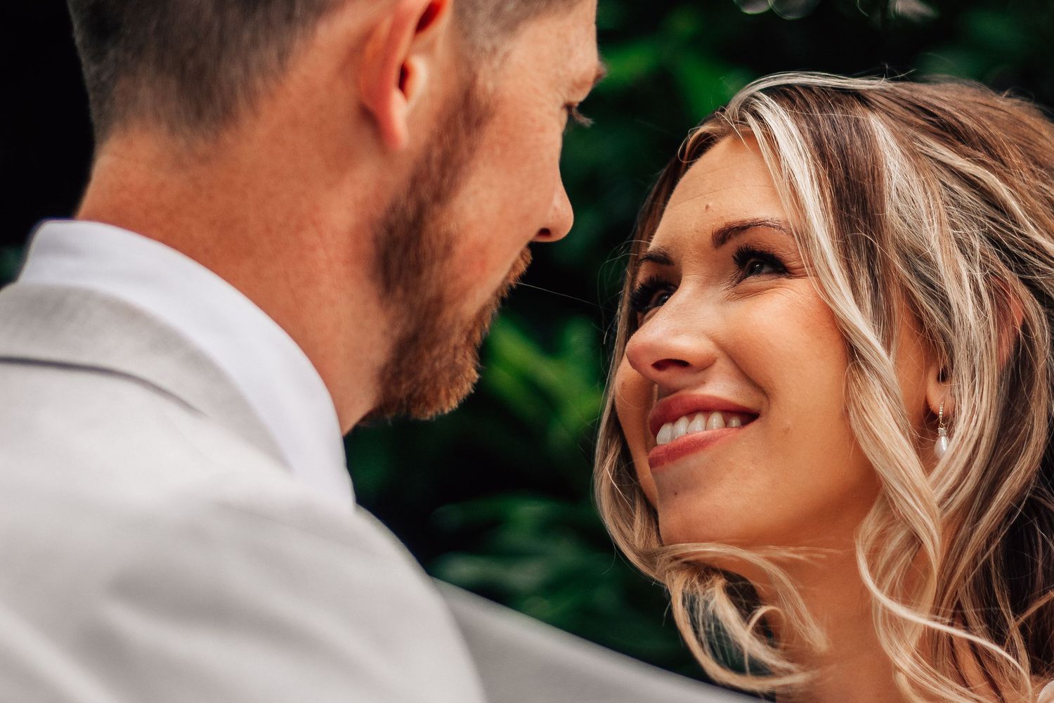 Bride and groom sharing an intimate moment, smiling at each other on their wedding day.