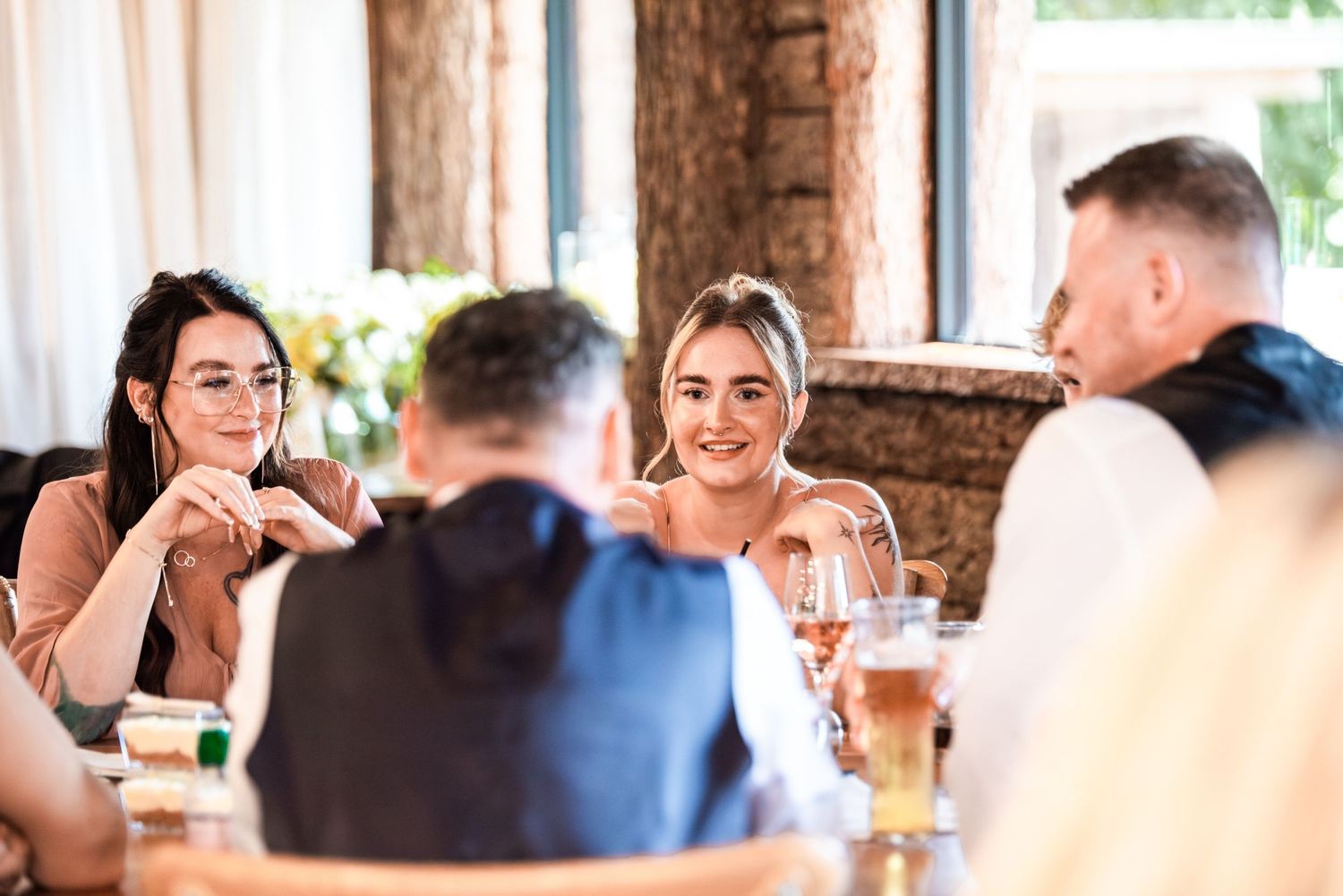 Group of friends enjoying drinks and conversation at a restaurant table in a bright, modern dining setting.