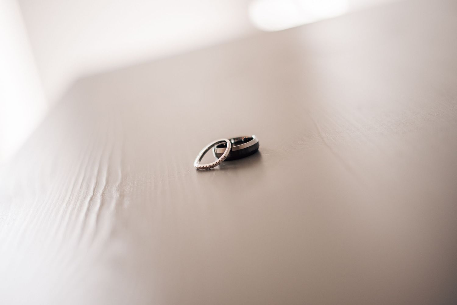 Two wedding rings resting on a white fabric surface in soft natural light.
