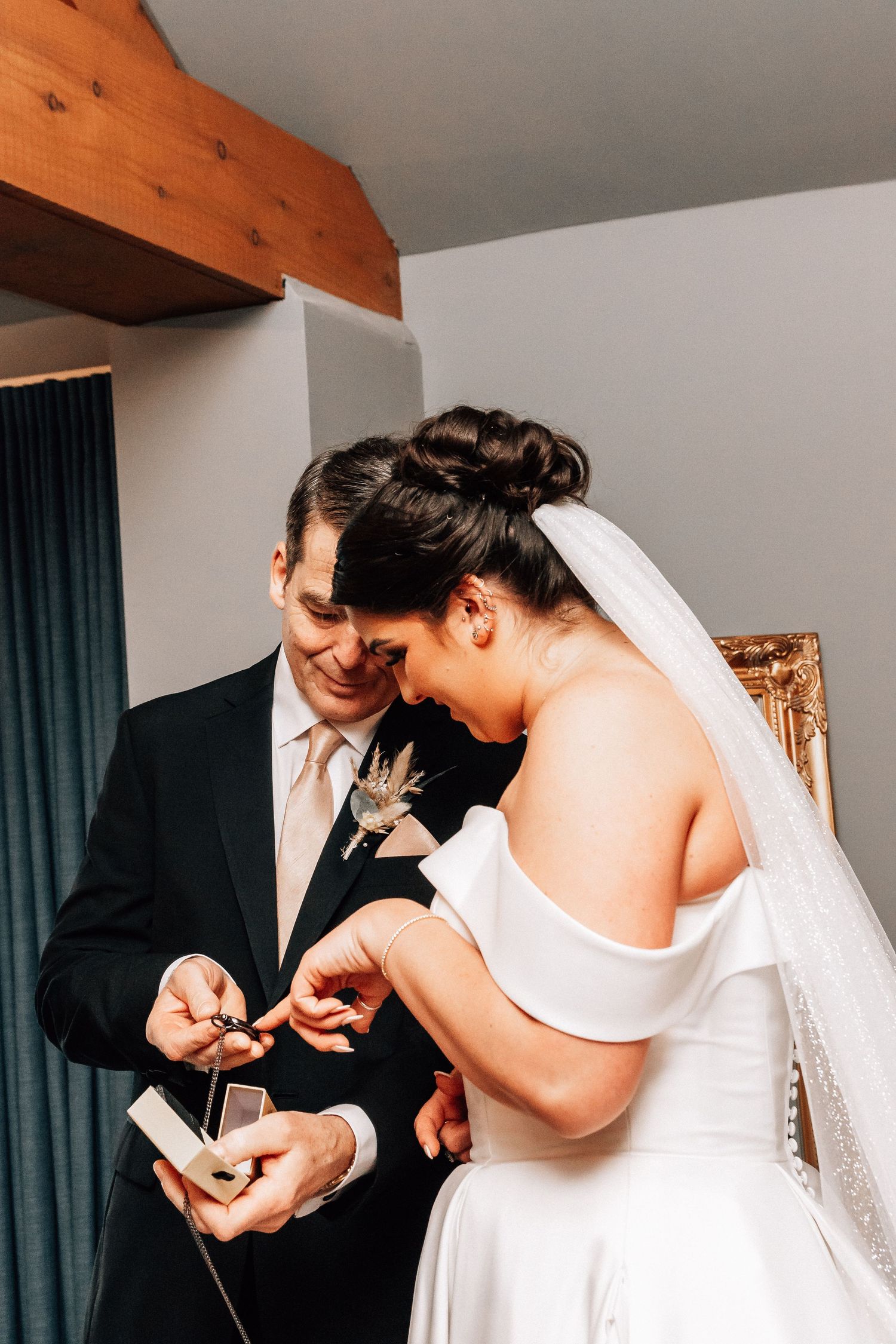 Bride and groom sharing a joyful moment indoors, exchanging rings in wedding attire, white gown and black suit.