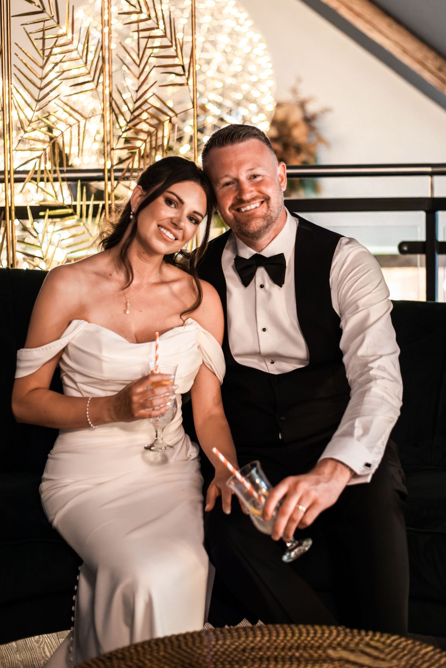 Bride and groom smiling and holding champagne glasses at their wedding reception.