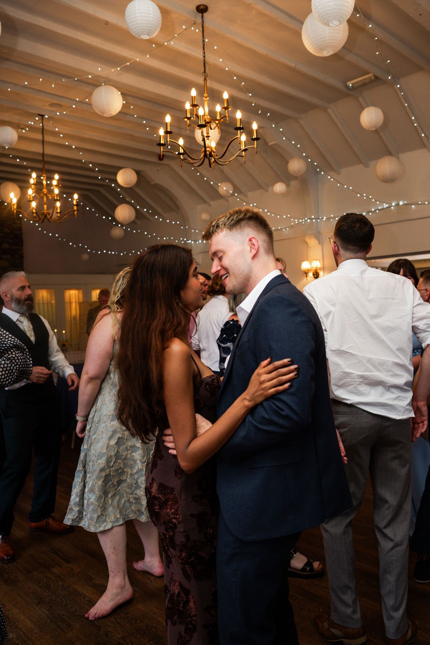 Couple sharing a romantic dance at a wedding reception with fairy lights and paper lanterns decorating the venue.