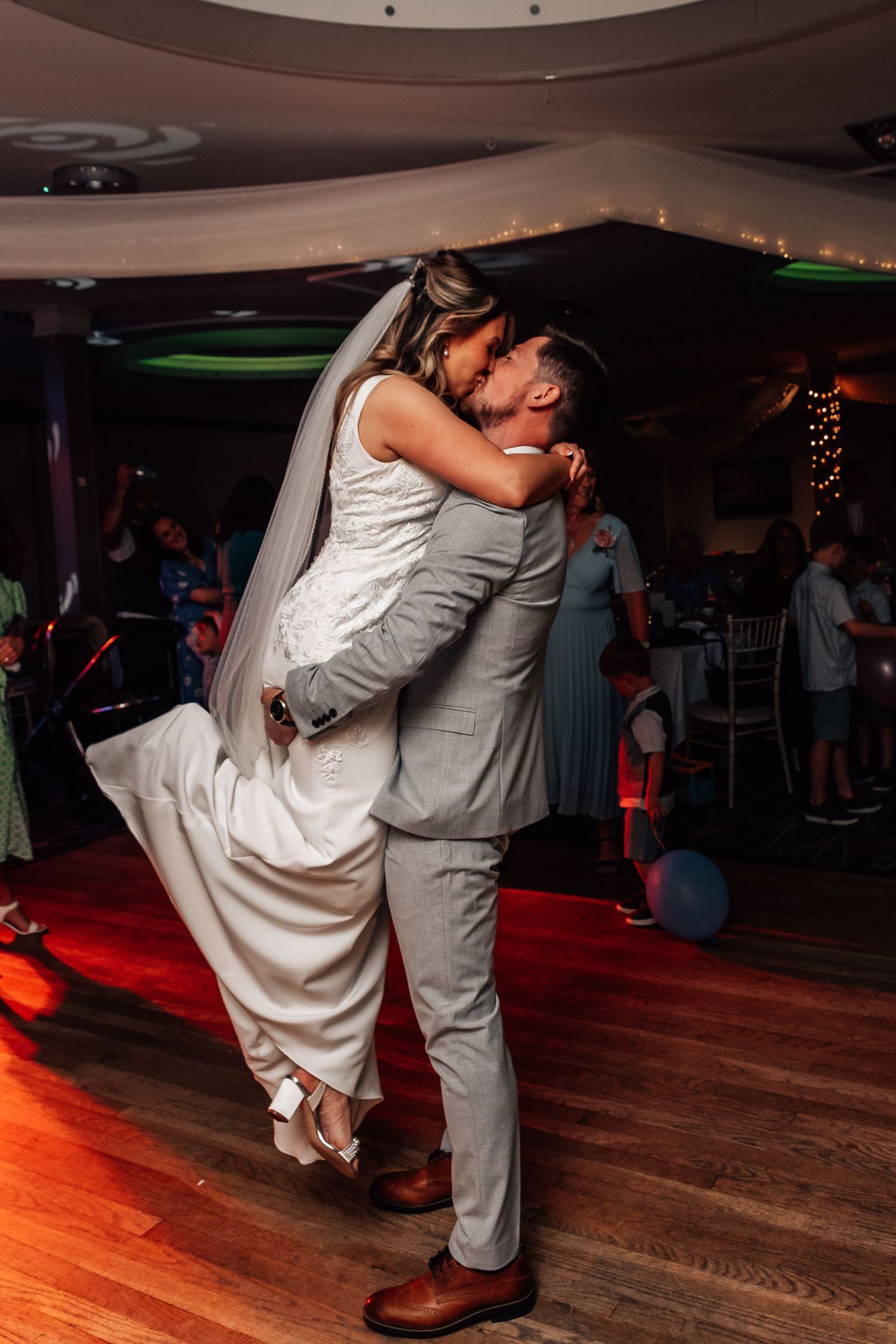 Groom lifting bride during first dance at wedding reception.