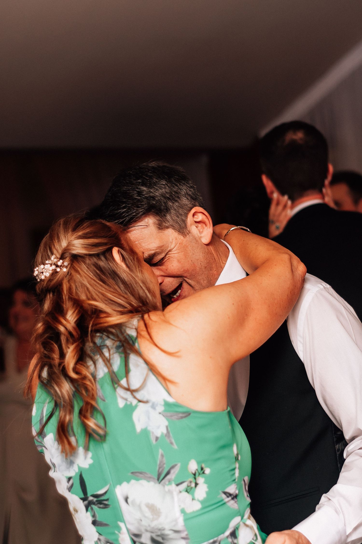 Couple shares an emotional embrace while dancing together at a warm and joyful wedding reception.