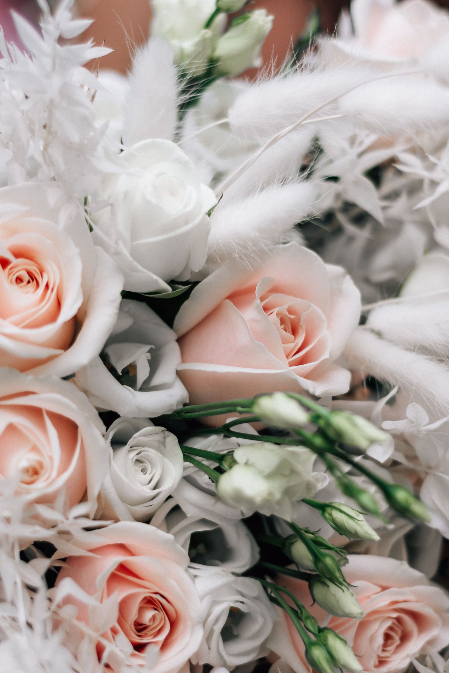 Elegant bridal bouquet featuring soft pink roses, white lisianthus, and fluffy pampas grass in a romantic arrangement.