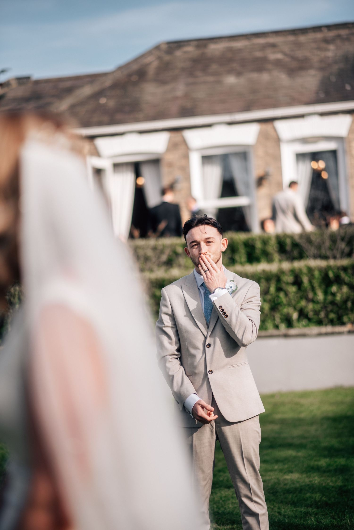 Emotional groom covers his mouth in awe as he sees his bride for the first time on their wedding day outdoors.