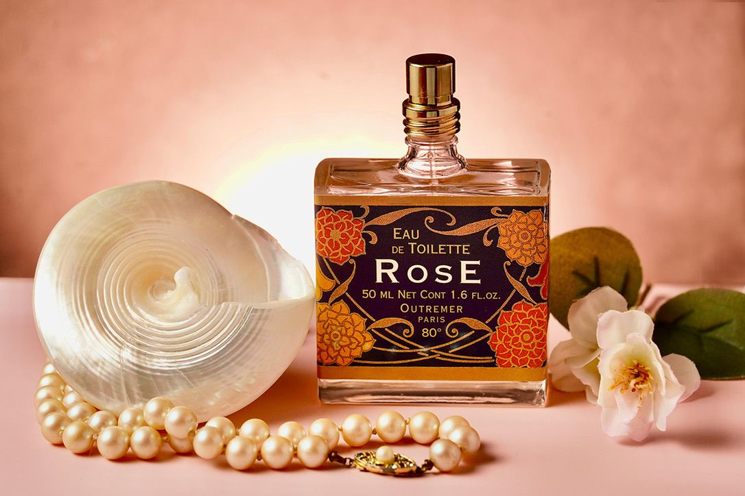 Luxury perfume bottles and pearl necklaces arranged artistically in warm lighting.