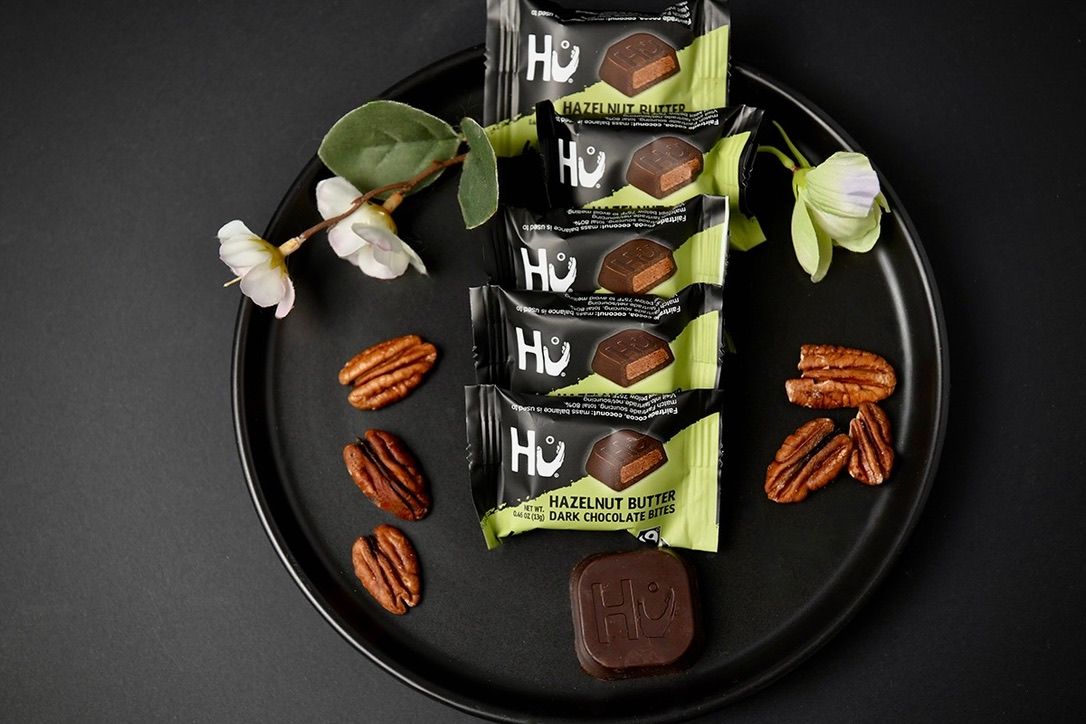 Chocolate bars with pecans arranged on dark background with dramatic lighting.