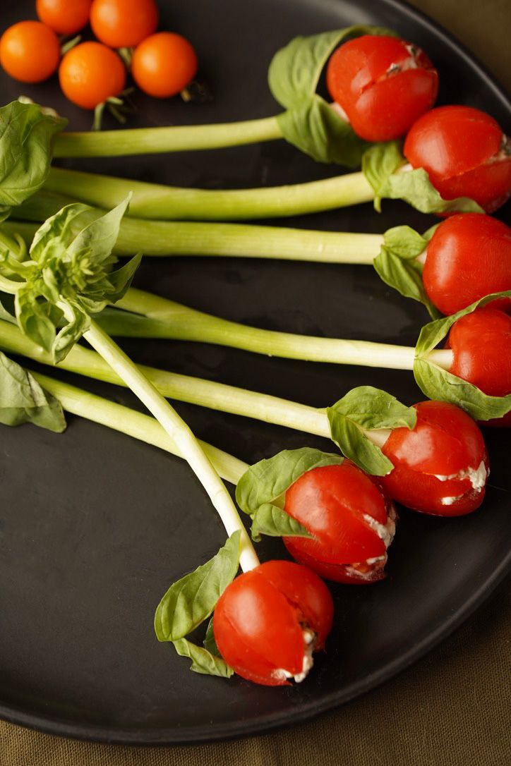 Fresh cherry tomatoes and celery stalks artfully arranged on a black plate.