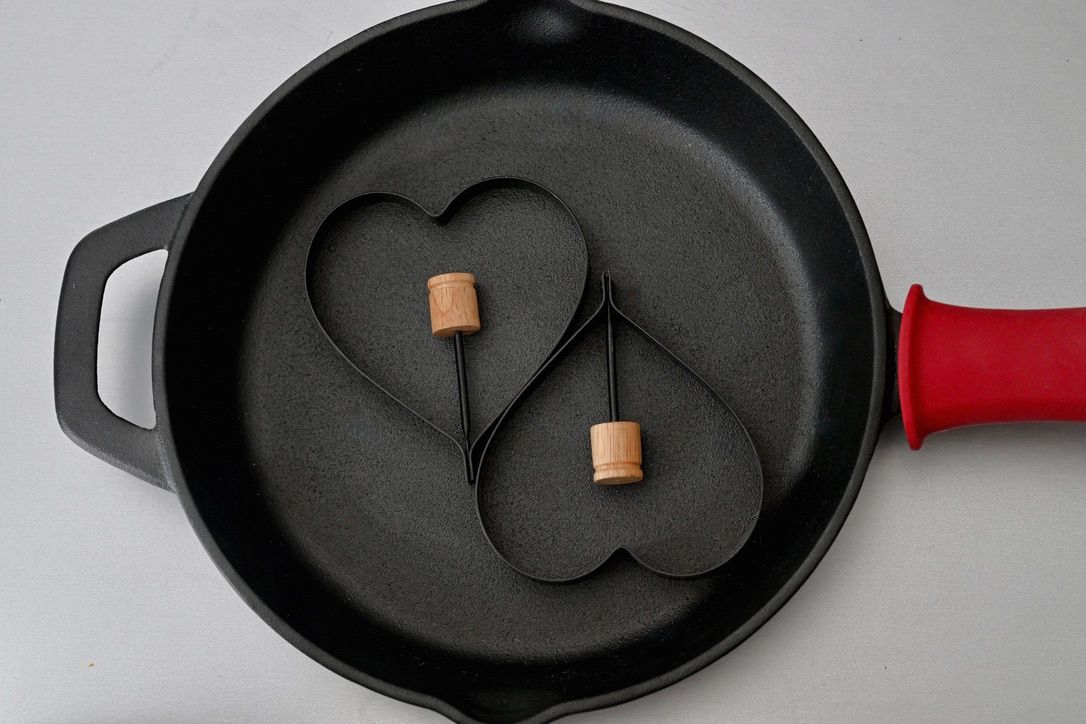 Black cast iron pan with pancake molds arranged in a minimalist composition.