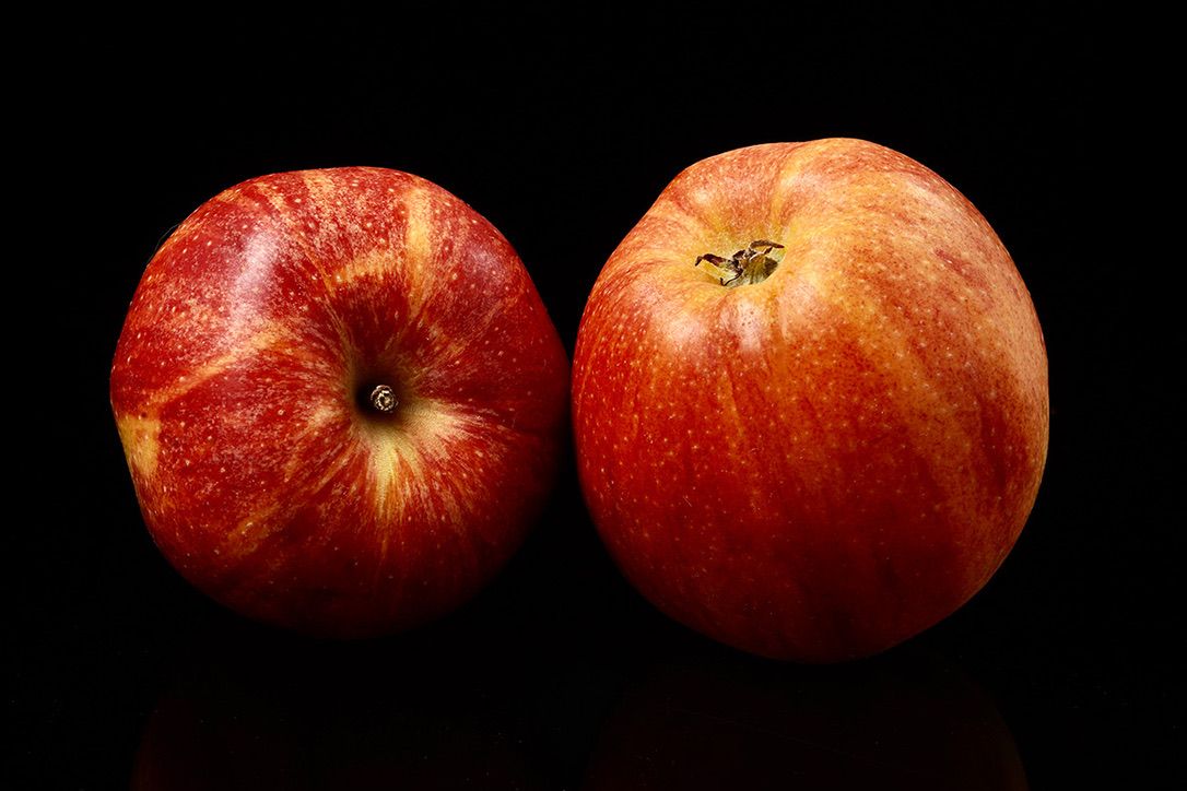 Fresh red apples arranged in a row against a black background showing their vibrant color and texture.