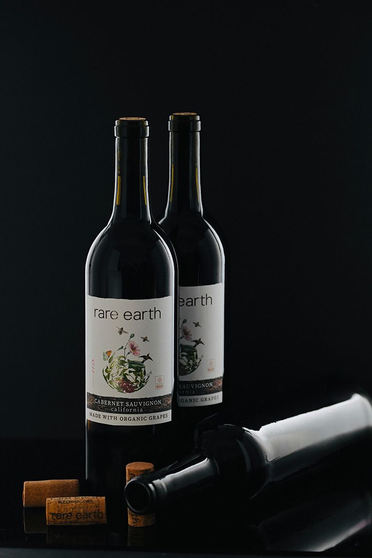 Dark wine bottles with vintage labels arranged artistically against a black background.