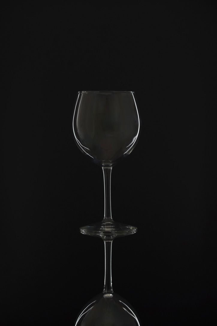 Empty wine glass on black background with reflection.