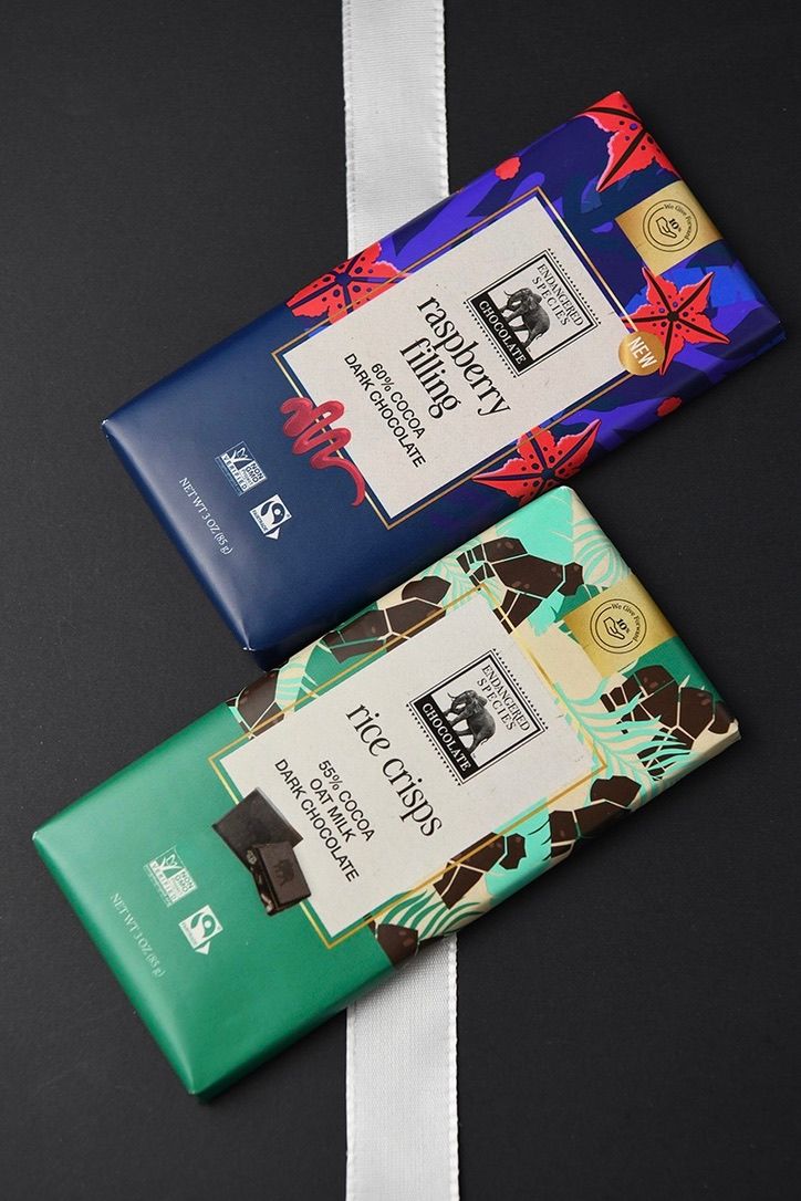 Luxury chocolate bars with colorful artistic packaging displayed on dark surface.