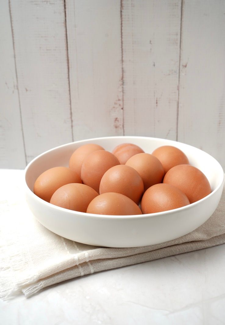 Brown eggs arranged in a white oval ceramic dish on light background.